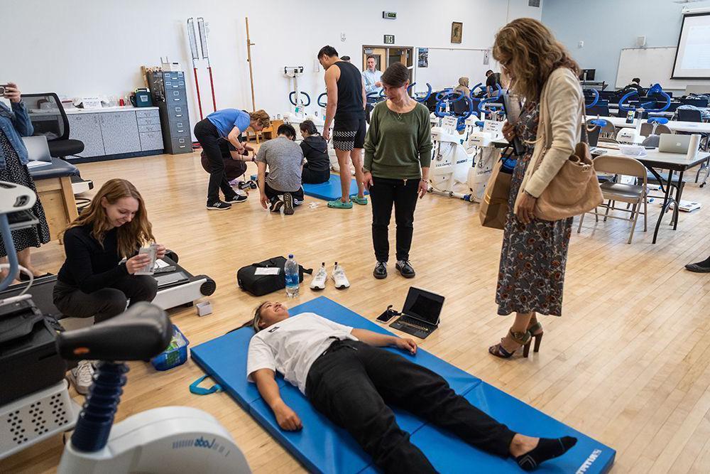 The president watching a student lay on a yoga matt at the college of health and human sciences tour.